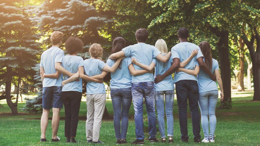 Group of happy volunteers embracing in park