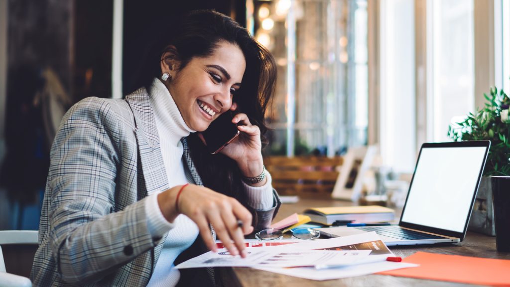 Cheerful remote worker calling on mobile creating project