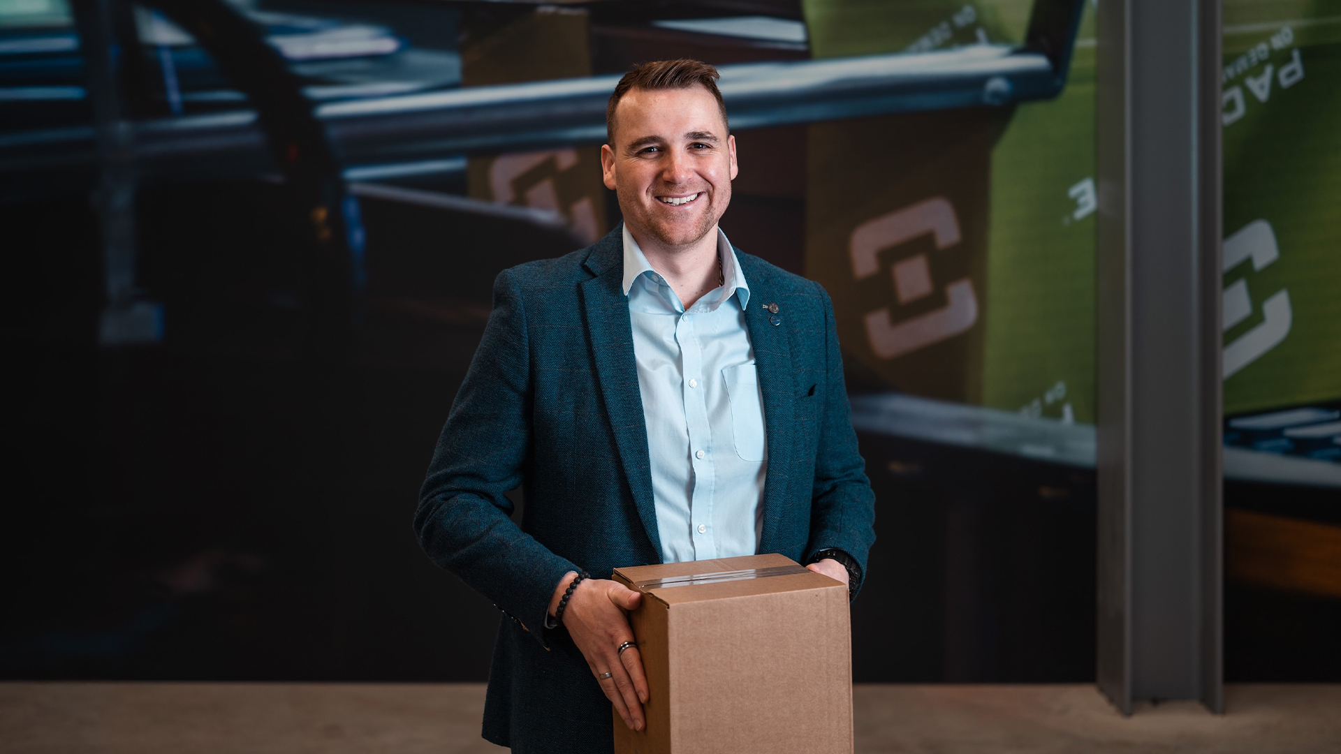 man in suit smiling and holding box